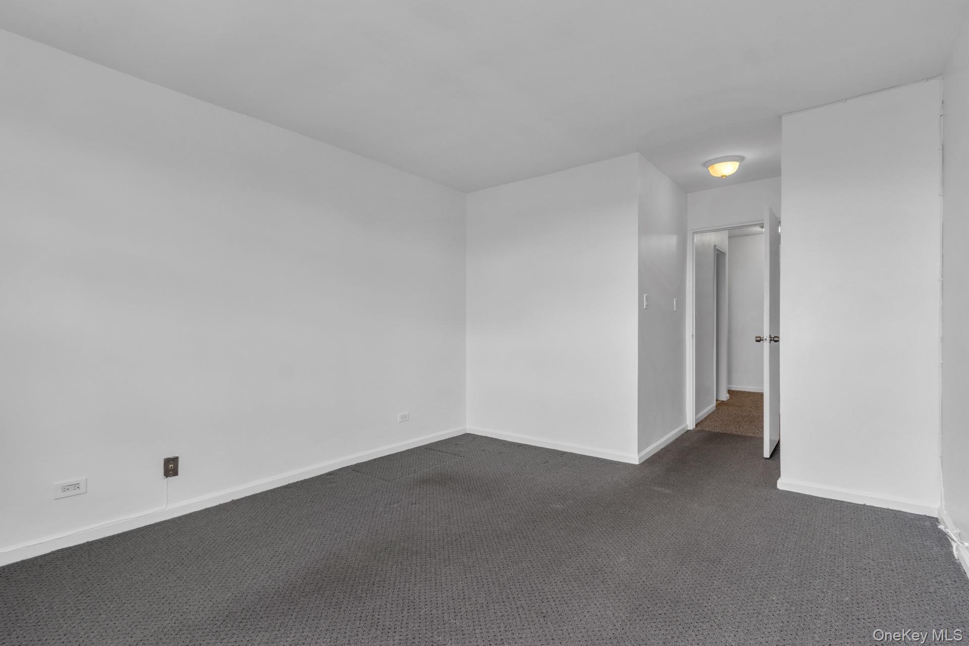 211-40 18th Avenue, Unit 6C Queens, NY 11360 - Photo 27 of 41 Empty room with dark carpet and baseboards