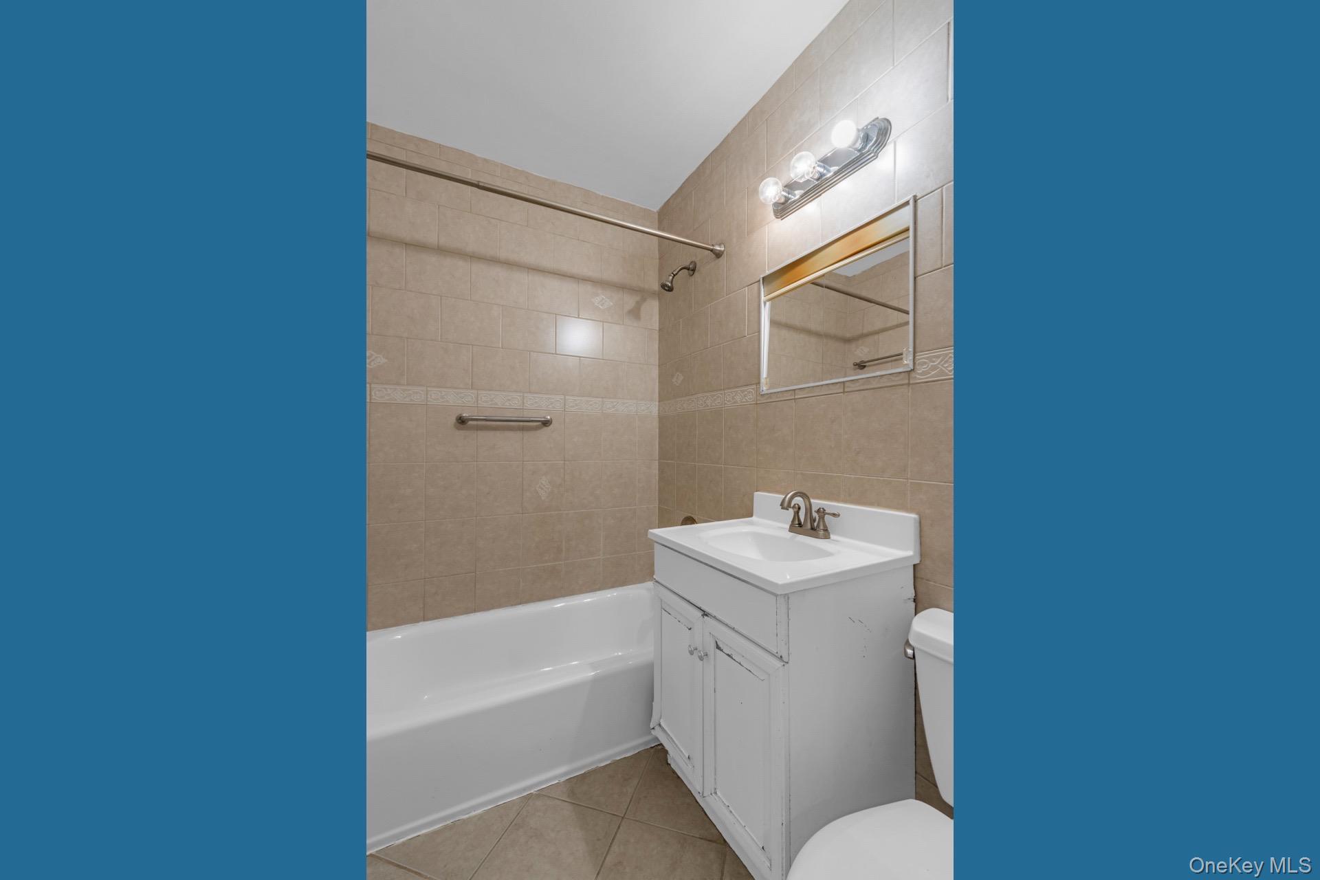 211-40 18th Avenue, Unit 6C Queens, NY 11360 - Photo 29 of 41 Full bath featuring vanity, tub / shower combination, tile walls, and light tile patterned flooring