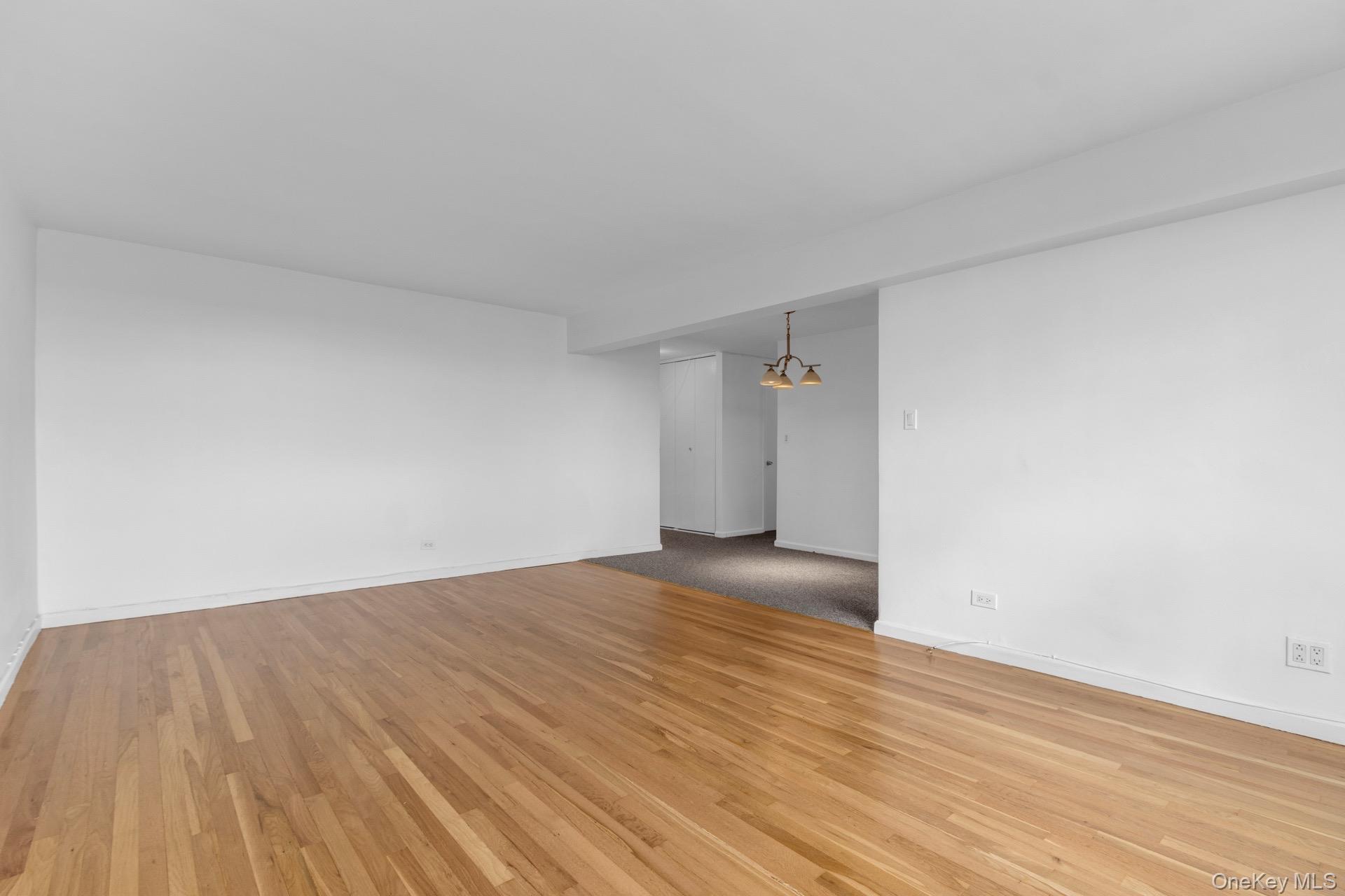 211-40 18th Avenue, Unit 6C Queens, NY 11360 - Photo 4 of 41 Empty room featuring light wood-type flooring and a chandelier