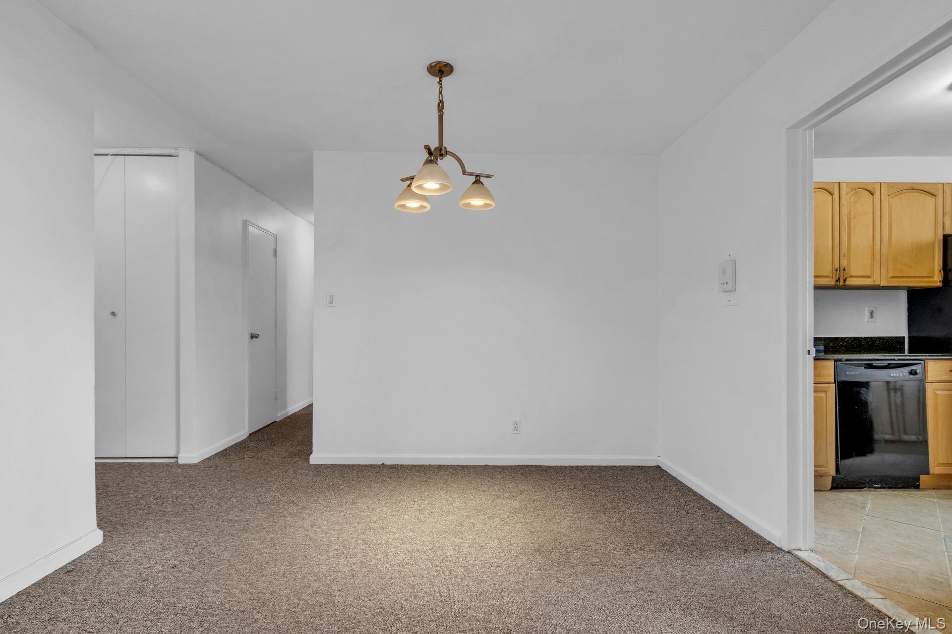 211-40 18th Avenue, Unit 6C Queens, NY 11360 - Photo 9 of 41 Unfurnished dining area with light carpet and a chandelier