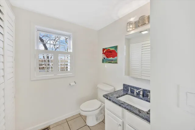 a bathroom with a granite countertop sink mirror vanity and toilet