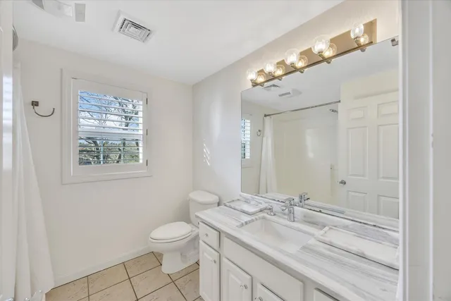 a bathroom with a granite countertop sink a toilet and a mirror