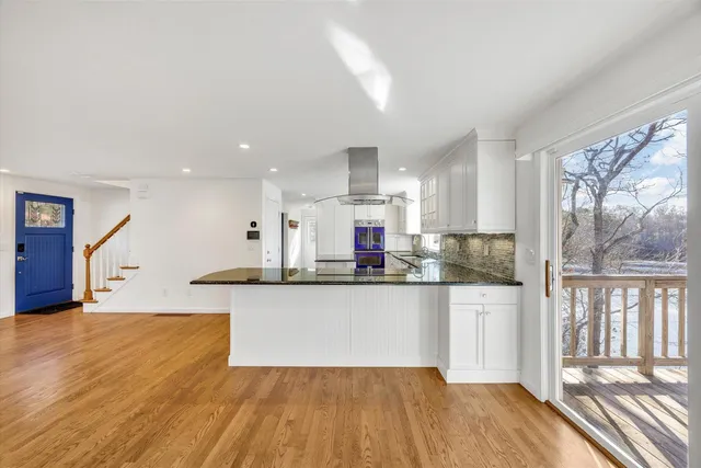 a kitchen with granite countertop a stove and white cabinets with wooden floor