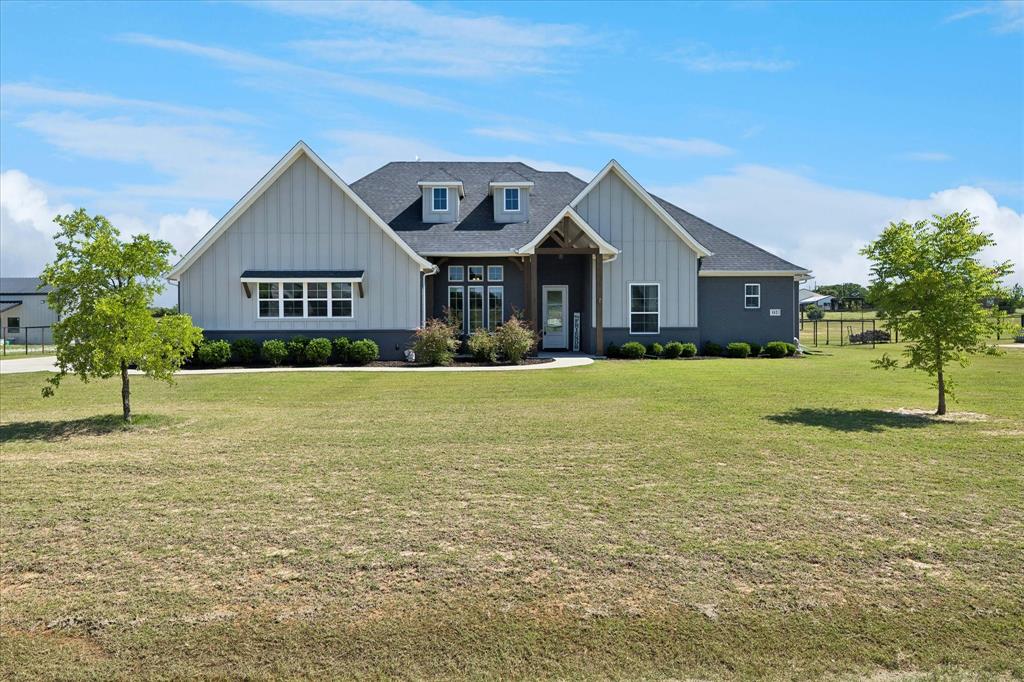 112 Friendship Way Boyd, TX 76023 - Photo 1 of 29 Modern farmhouse-style residence featuring a gray and white board-and-batten and horizontal siding exterior, a dark shingle roof, and multiple dormer windows