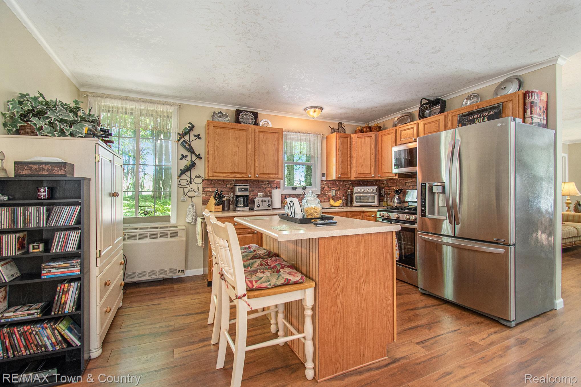 1293 Bellinger Road Gladwin, MI 48624 - Photo 8 of 27 Wood-finish flooring, central island with countertop, natural wood cabinetry, stainless steel appliances, and a tiled backsplash