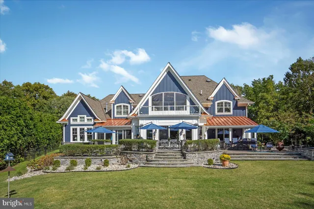 a view of a patio with table and chairs under an umbrella with large trees