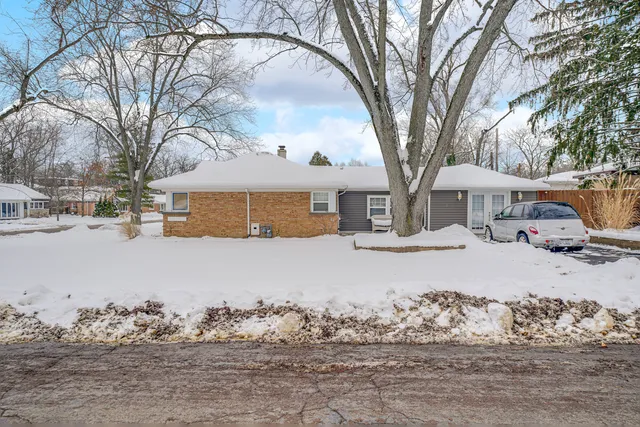 a front view of a house with a yard covered in snow