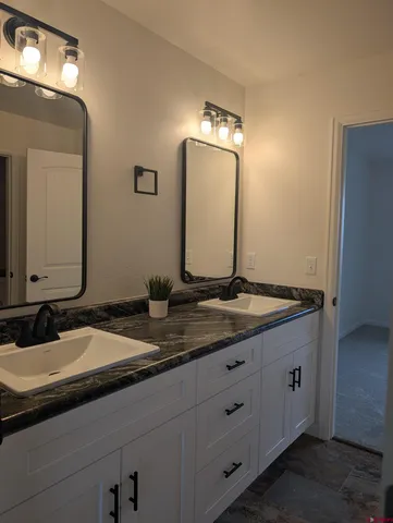 a bathroom with a granite countertop sink and a mirror