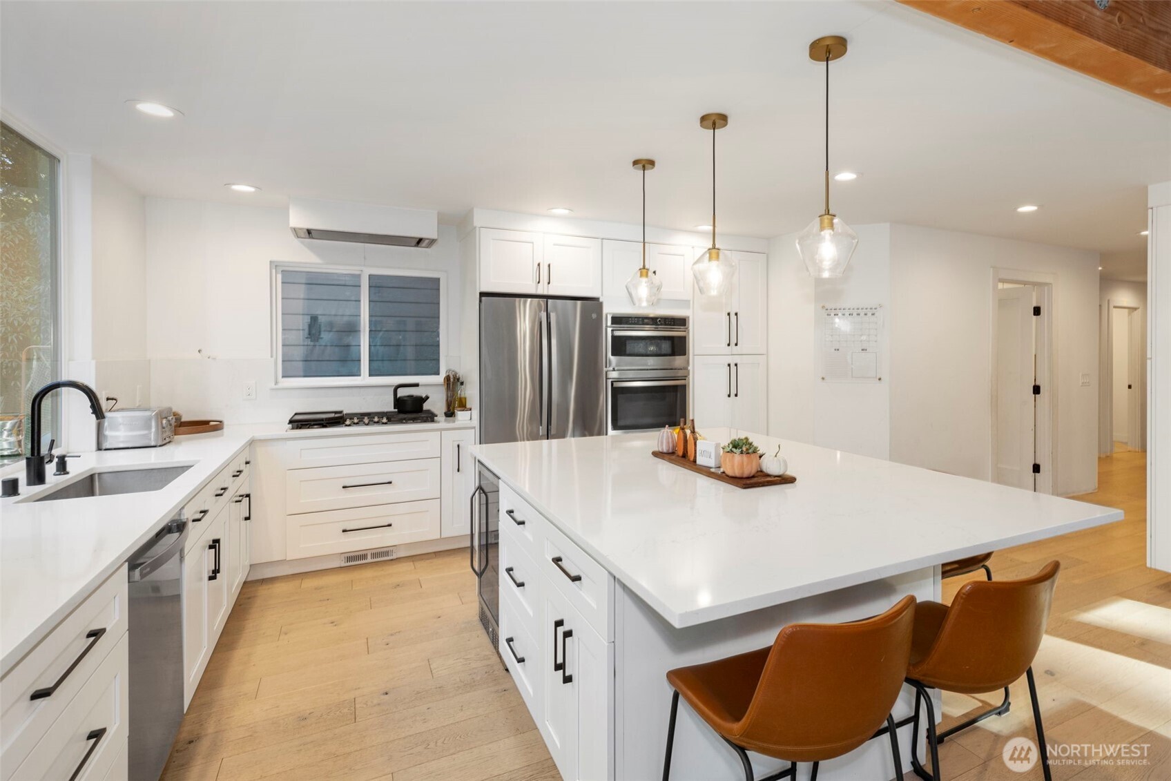 16455 Agate Point Road Northeast Bainbridge Island, WA 98110 - Photo 9 of 26 a kitchen with stainless steel appliances kitchen island a table chairs sink refrigerator and cabinets