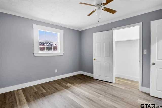 a view of empty room with wooden floor and fan