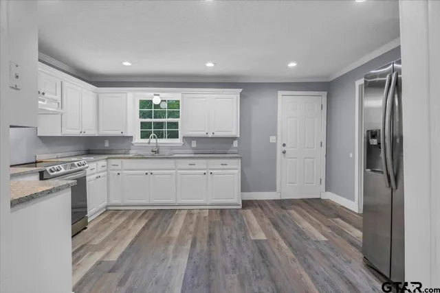 a kitchen with a hard wood floor white cabinets and stainless steel appliances