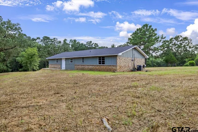 a front view of house with yard and trees in the background