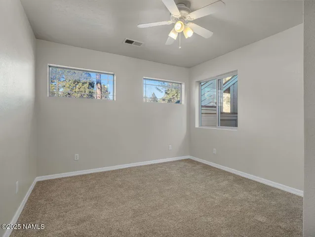 an empty room with windows and fan