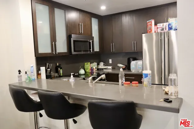 a kitchen with stainless steel appliances a sink a microwave a refrigerator and cabinets