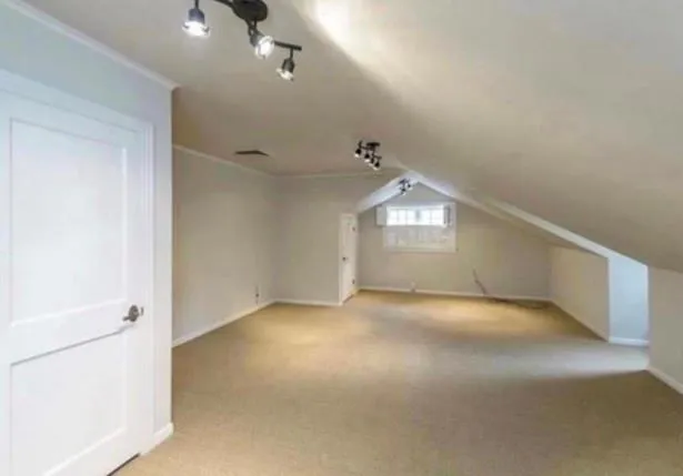 an empty room with chandelier fan and windows