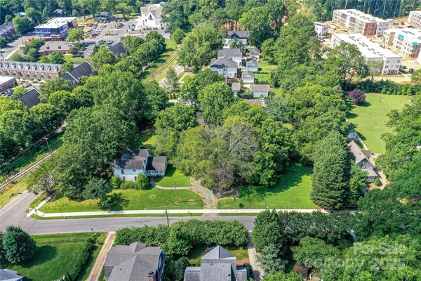 an aerial view of residential houses with outdoor space and trees