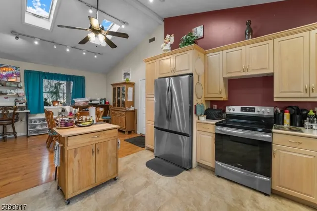 a kitchen with stainless steel appliances granite countertop a refrigerator a stove a sink dishwasher a refrigerator and a dining table with wooden floor
