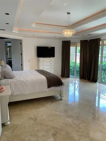 a bedroom with a large bed flat screen tv and a large window