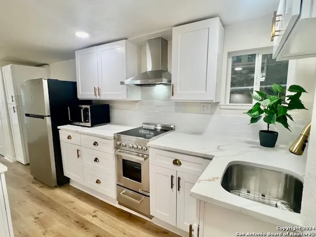 a kitchen with stainless steel appliances white cabinets a sink a stove a refrigerator and a refrigerator