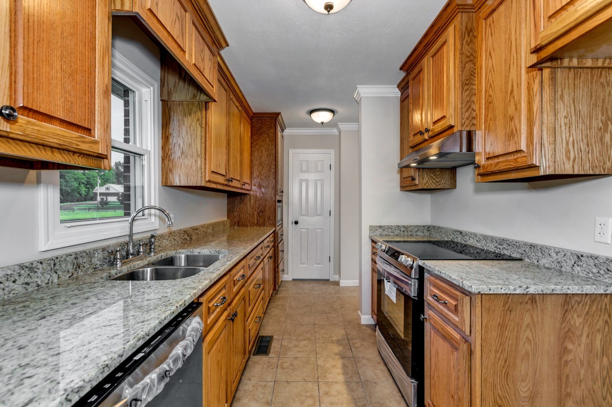 477 Holt Hollow Road Prospect, TN 38477 - Photo 8 of 34 a kitchen with granite countertop a sink a stove and a wooden cabinets