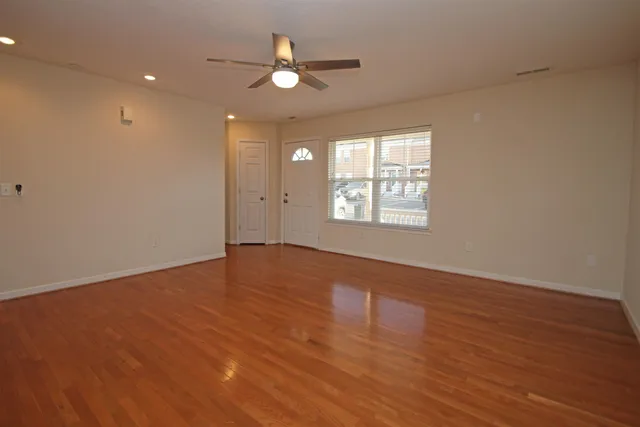 an empty room with wooden floor and windows