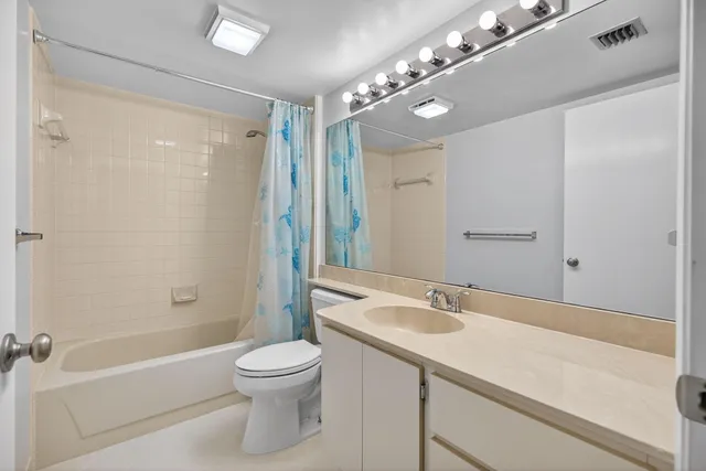 a bathroom with a granite countertop sink a toilet a mirror and shower