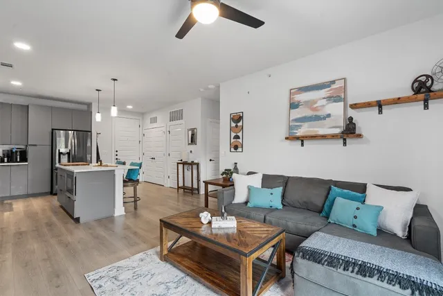 a living room with furniture kitchen view and a chandelier