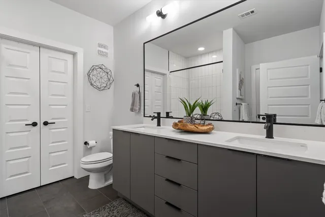 a bathroom with a double vanity sink toilet and a mirror