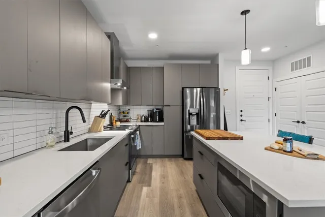 a kitchen with stainless steel appliances a sink dishwasher a stove a refrigerator and cabinets with wooden floor