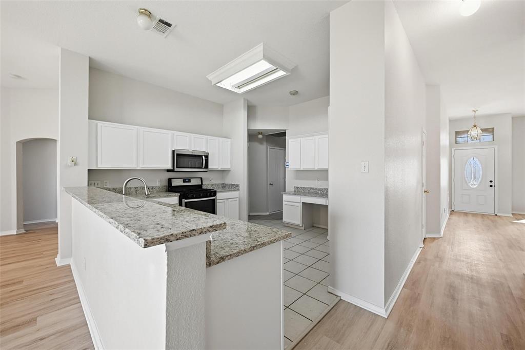 1703 Caladium Drive Corinth, TX 76210 - Photo 8 of 24 a kitchen with granite countertop a refrigerator oven a sink dishwasher and white cabinets with wooden floor