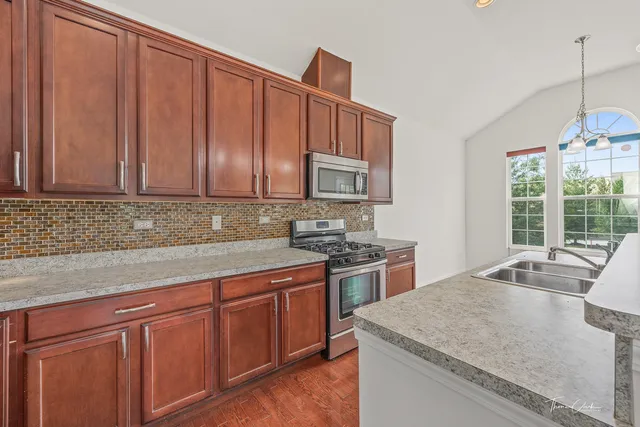 a kitchen with stainless steel appliances granite countertop wooden cabinets a stove a sink and dishwasher