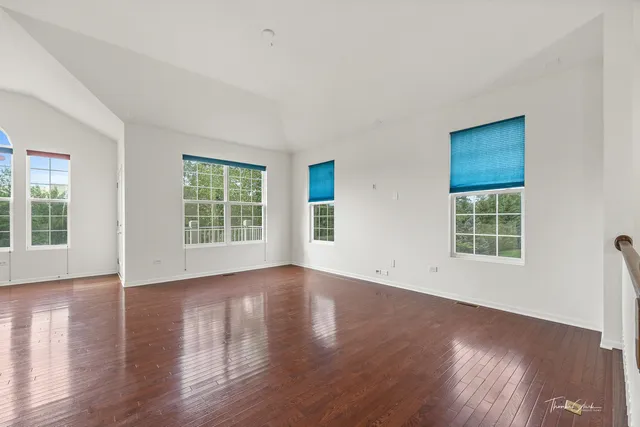 a view of an empty room with wooden floor and windows
