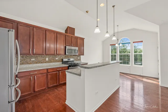 a kitchen with stainless steel appliances granite countertop a stove a sink dishwasher and a refrigerator with wooden floor