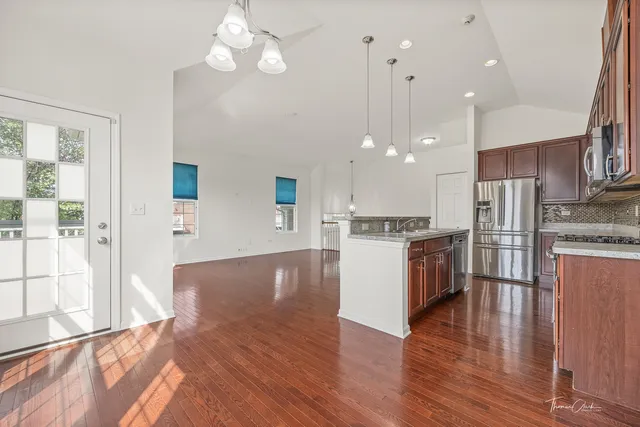 a large kitchen with stainless steel appliances kitchen island a large counter top and wooden floor