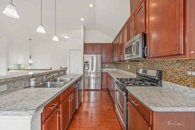 a kitchen with stainless steel appliances granite countertop a sink a stove and a refrigerator