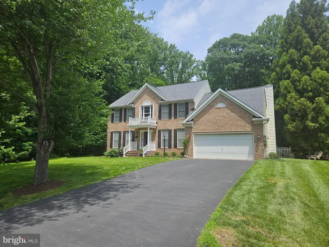 a front view of a house with a garden and trees