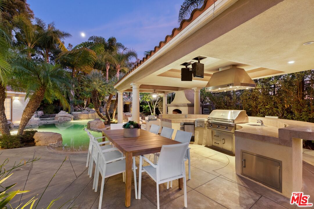 2 Arborwood Irvine, CA 92620 - Photo 23 of 26 a view of a patio with couches table and chairs under an umbrella with a barbeque grill and plants