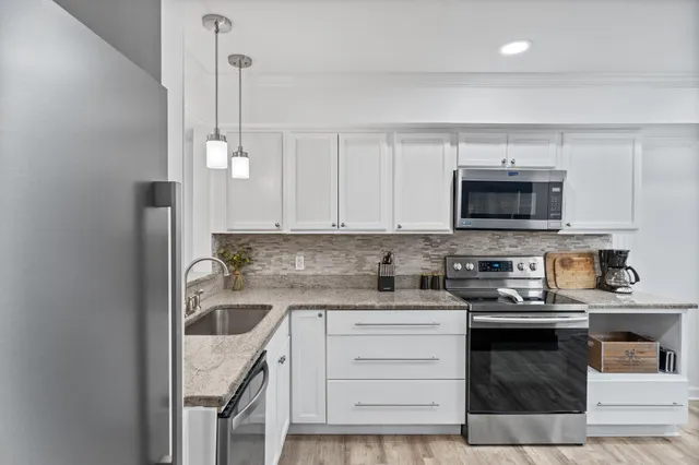 a kitchen with granite countertop a sink a stove and microwave