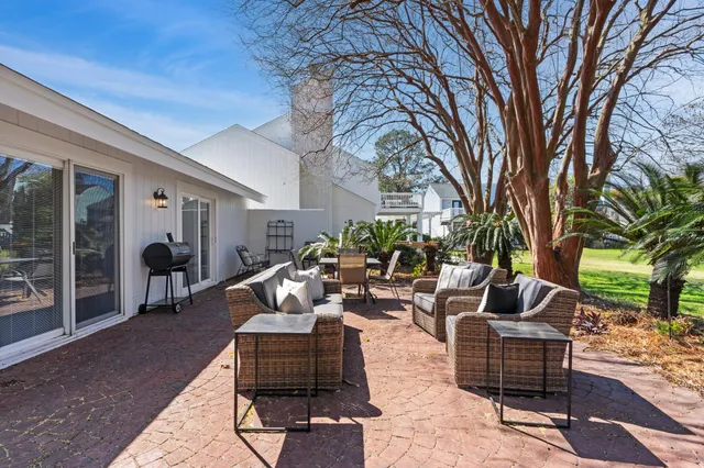 a view of a backyard with table and chairs potted plants and large tree