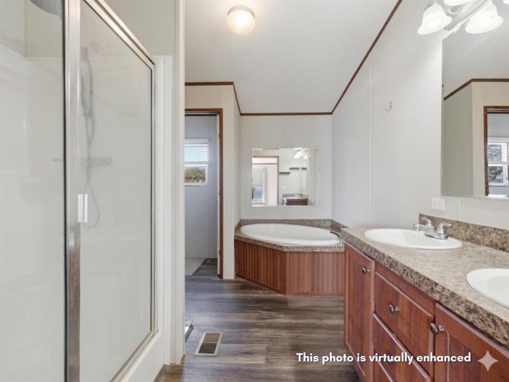 2722 Denver Road Sunset, TX 76270 - Photo 5 of 19 Bathroom featuring a glass-enclosed shower, a built-in soaking tub with wood-finish paneling, a double vanity with two undermount sinks, and wood-finish flooring