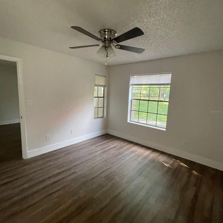238 Afton Square, Unit 103 Altamonte Springs, FL 32714 - Photo 5 of 16 an empty room with wooden floor fan and windows