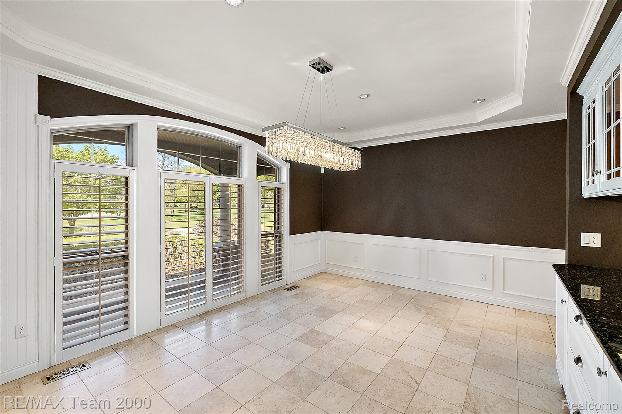 630 Sheldon Court Rochester, MI 48306 - Photo 22 of 94 Unfurnished dining area featuring ornamental molding, a wainscoted wall, suspended lighting, a decorative wall, and light tile patterned flooring