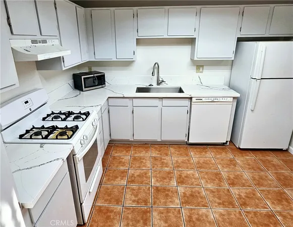 a kitchen with a sink a stove a refrigerator and cabinets
