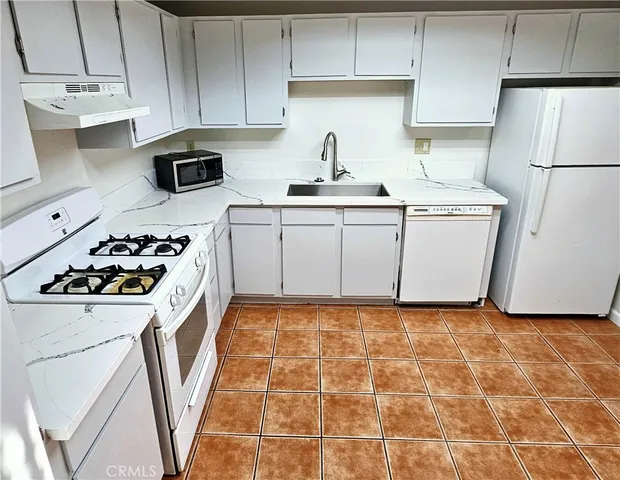a kitchen with a sink a stove a refrigerator and cabinets