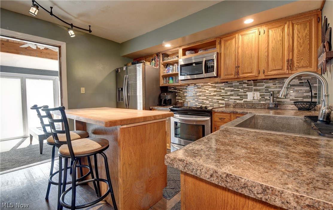 3963 Ranfield Road Kent, OH 44240 - Photo 6 of 23 Kitchen featuring backsplash, rail lighting, appliances with stainless steel finishes, sink, and wood-style floors