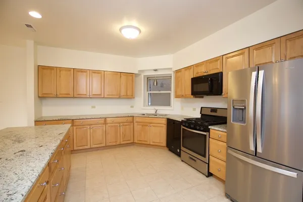 a kitchen with granite countertop a refrigerator stove top oven and sink