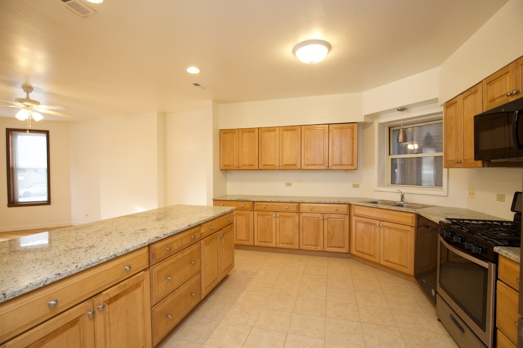 6713 North Sheridan Road, Unit 2N Chicago, IL 60626 - Photo 4 of 20 a large kitchen with stainless steel appliances granite countertop a sink and cabinets