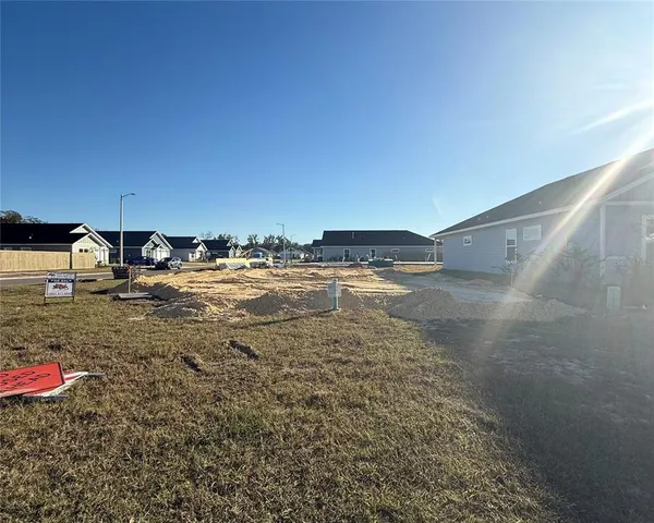 a view of a white house with a yard plants and large tree