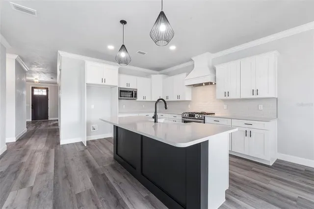 a kitchen with stainless steel appliances granite countertop a sink a stove and a wooden floors