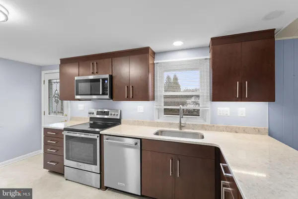 a large kitchen with granite countertop a large counter top stainless steel appliances and cabinets